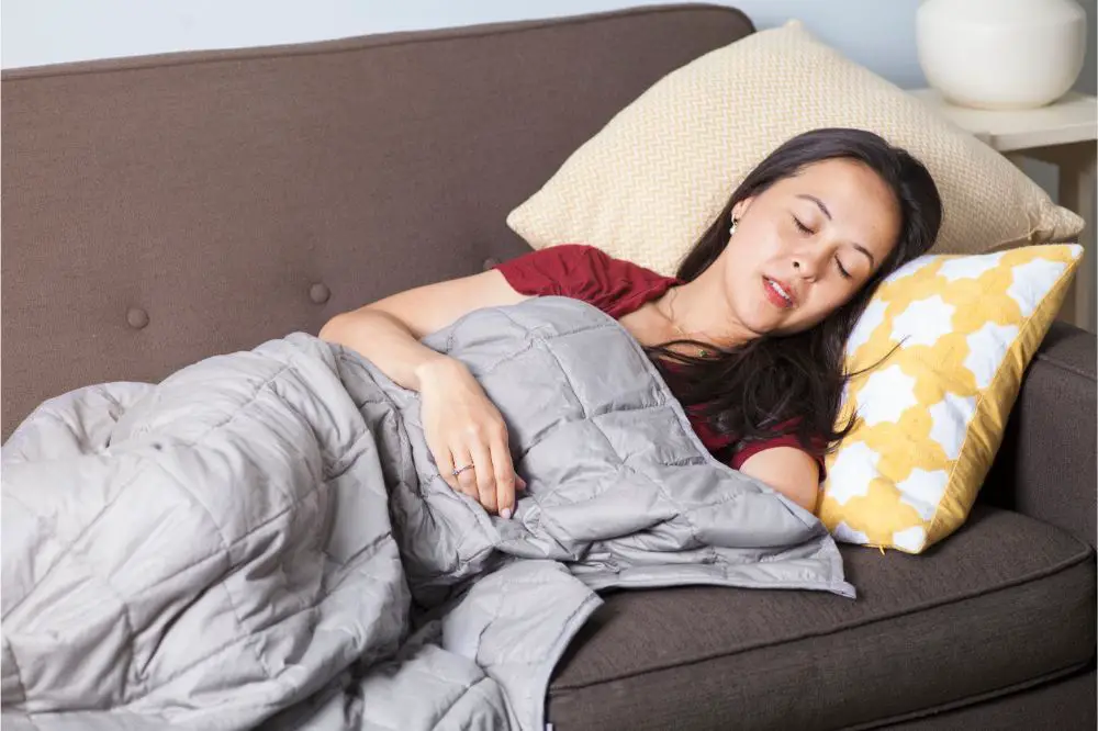 Woman sleeps on couch with weighted blanket