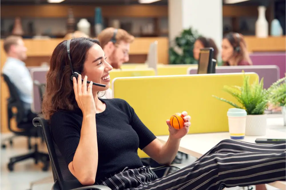 Businesswoman Wearing Headset Playing With Stress Ball Talking