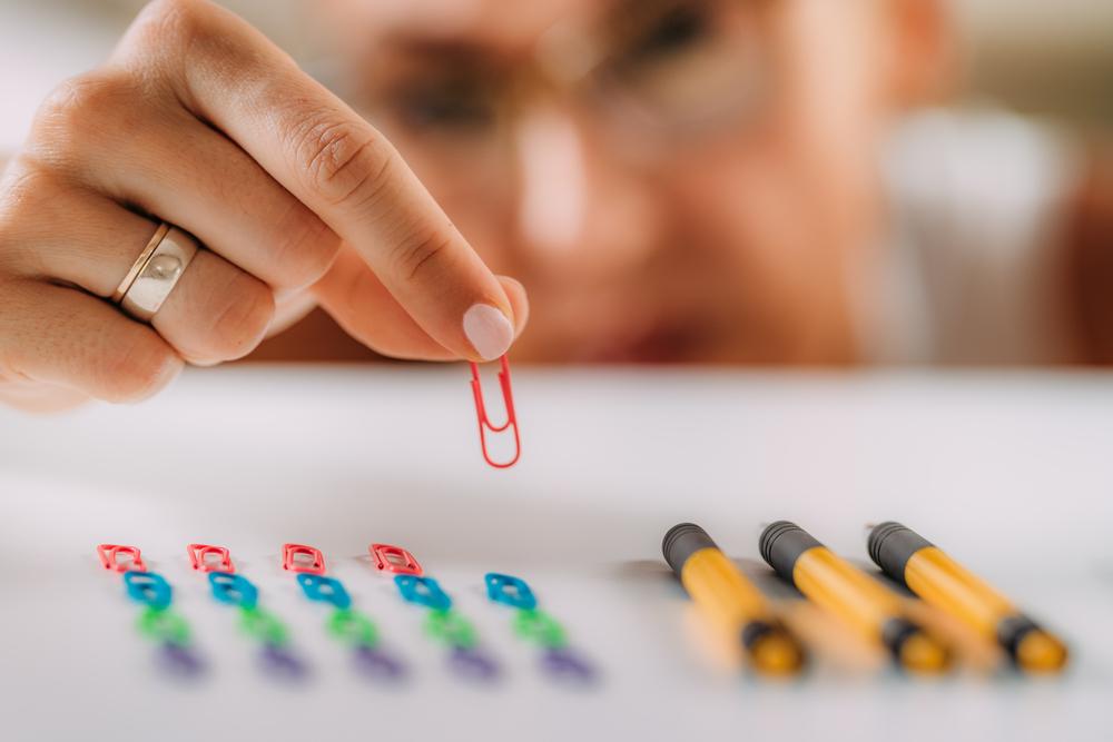 Woman with OCD – Obsessive compulsive disorder concept. Placing paperclips in a straight line.